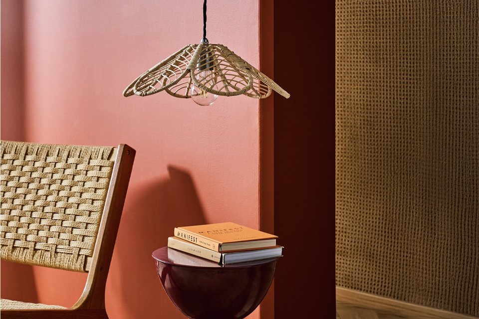 Woven wicker ceiling light above side table and accent chair to make a cosy reading corner.